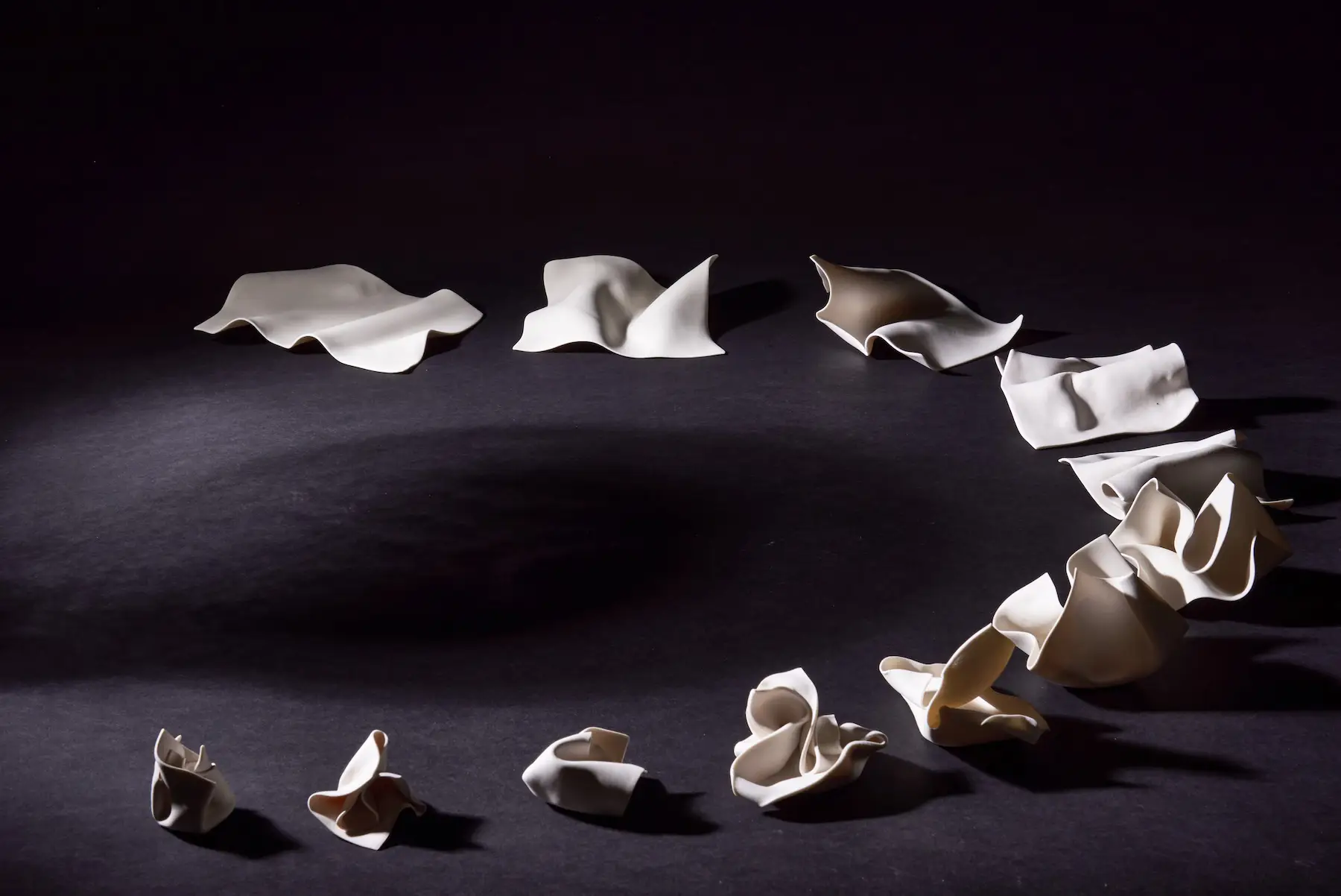 Wall Installation — Screwed Up wall installation of multiple hand-built porcelain forms resembling crumpled paper, arranged as a sculptural group. Studio Willis.